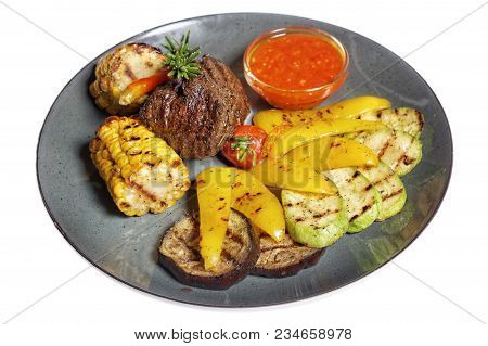 Fried Meat With Garnish Of Pepper, Zucchini, Tomato And Corn With Ajika Sauce Served On A Gray Plate
