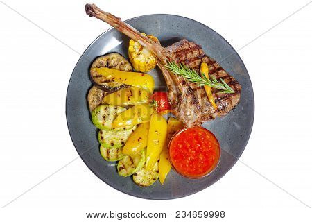 Fried Meat With Garnish Of Pepper, Zucchini, Tomato And Corn With Ajika Sauce Served On A Gray Plate