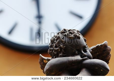 Cupid Is Sitting In Front Of The Big Clock.