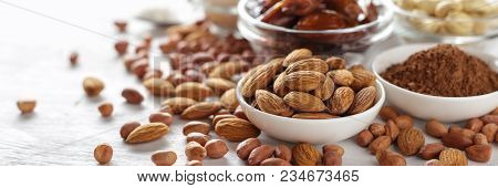 Almond, Peanut, Cocoa Powder And Cashew On White Wooden Table. Banner With Copy Space.