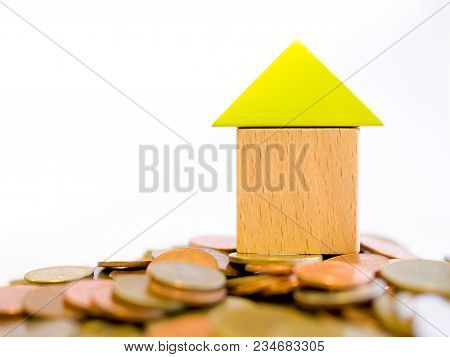 Coins And Blocks -  Close Up Small Blocks House Standing On A Pile Of Coins. The Concept Of Purchase