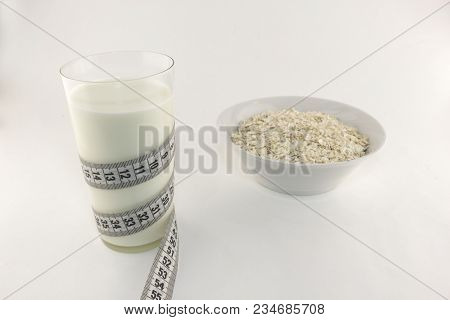 A Glass Of Milk And A Centimeter Tape Of Oatmeal White Background