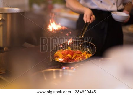 Chef cooking and doing flambe on food in restaurant kitchen