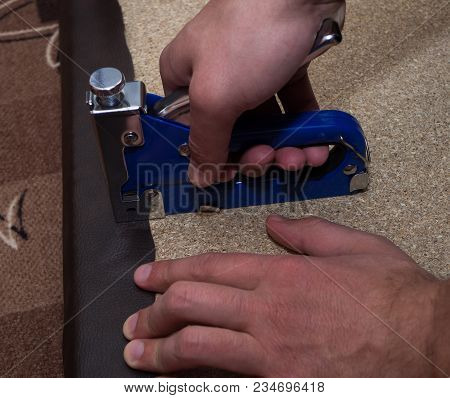 Two Man Hands Using Stapler Upholstering Paricle Board With Leatherette.close-up