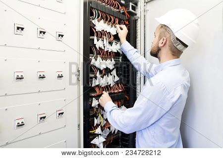 Service Engineer In Data Center. Worker In Helmet Near The Switches Of Optical Cables. Telecommunica