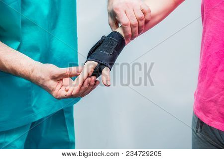 Close Up Neurologist Doctor, Therapist Puts On Wrist Retainer On Young Female Patient's Hand. Pain T
