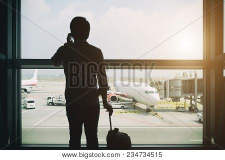 Young Businessman Stand At Terminal In Internatianal Airport During Sunset And Talking On The Phone 