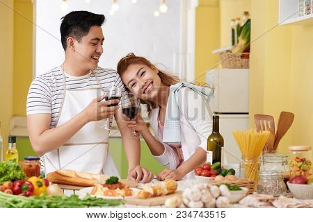 Happy Beautiful Couple In Love Enjoying Wine And Cooking Dinner