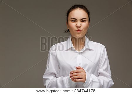 Beautiful Girl In A White Shirt Shows Emotions. On A Light Background.