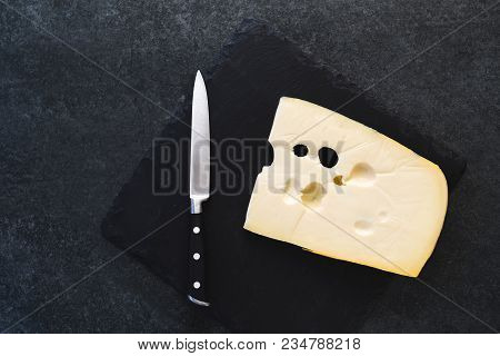 An Appetizing Solid Cheese On A Black Plate On A Gray Stone Background