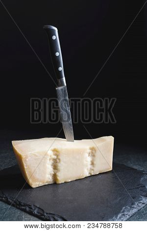 An Appetizing Solid Cheese On A Black Plate On A Gray Stone Background