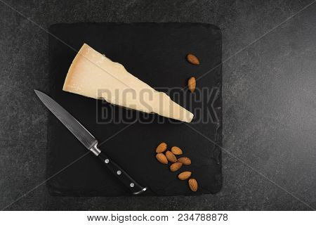 An Appetizing Solid Cheese On A Black Plate On A Gray Stone Background