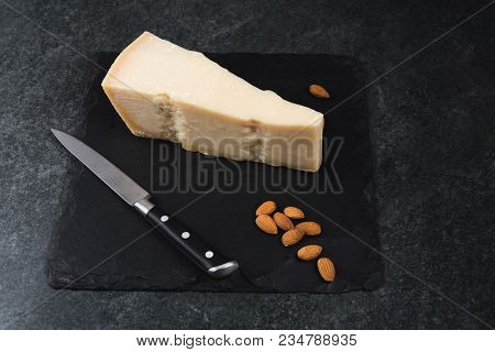 An Appetizing Solid Cheese On A Black Plate On A Gray Stone Background
