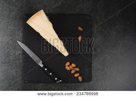An Appetizing Solid Cheese On A Black Plate On A Gray Stone Background