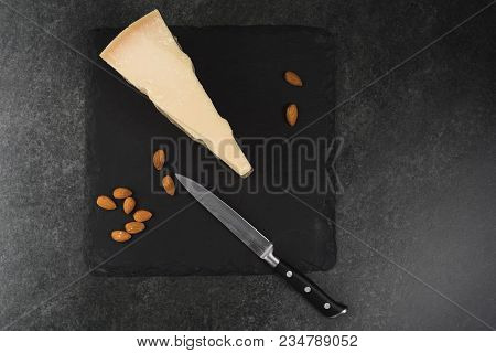 An Appetizing Solid Cheese On A Black Plate On A Gray Stone Background