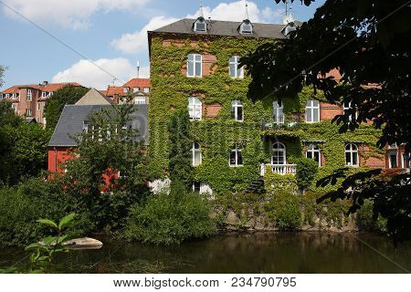 House In Ivy On The River Bank In Odense In Denmark