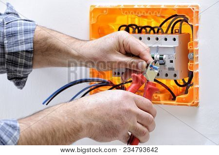 Electrician Technician Working On A Residential Electric Panel, Cuts The Cable With A Cable Cutter