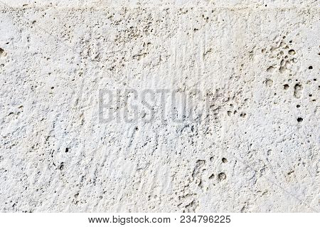 Close-up Deep Texture Of White-painted Porous Stone On The Facade Of The Building. Stoned Wall Backg