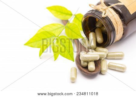 Green Herb Powder Capsules On Wooden Spoon Isolate On White