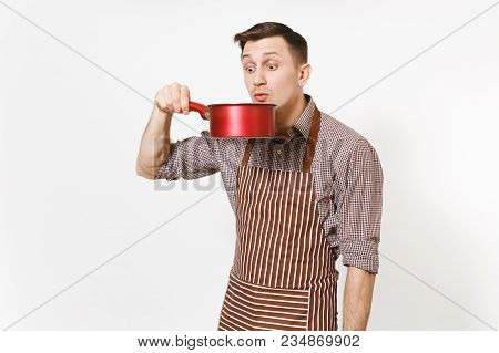 Young Fun Crazy Man Chef Or Waiter In Striped Brown Apron, Shirt Tasting From Red Empty Stewpan On H