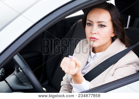 Boorishness on the road. Young woman is showing her fist to someone