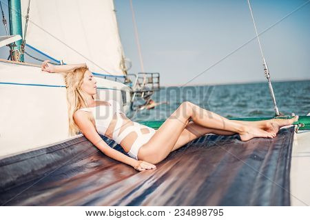 Woman In Fashion White Swimsuit Sitting On Yacht