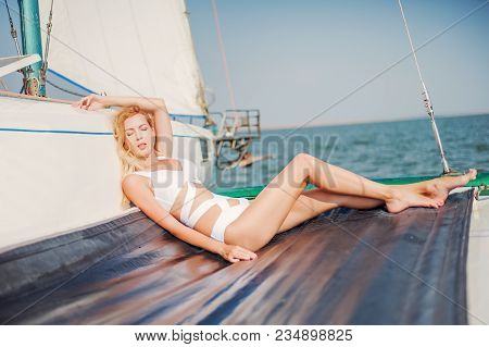 Woman In Fashion White Swimsuit Sitting On Yacht
