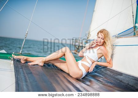 Woman In Fashion White Swimsuit Sitting On Yacht