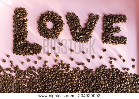 Spilled Roasted Coffee Beans On A Pink Background With A Love Inscription.