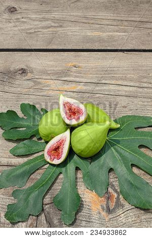 Halved Fig On Figs And Fig Leafs, Vertical, Wood Board As Background, Copy Space