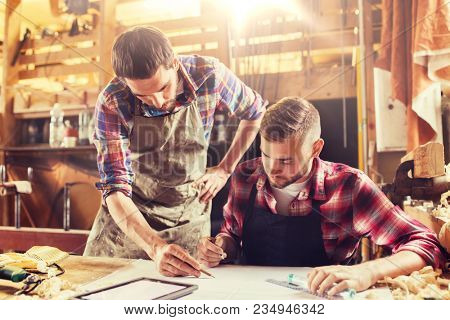 profession, technology and people concept - two workmen with tablet pc computer and blueprint at workshop