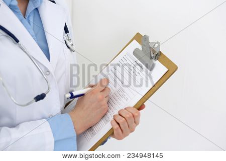 Female Doctor Filling Up Medical Form On Clipboard Closeup.  Physician Finishing Up Examining His Pa