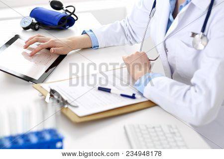 Woman Doctor Using Tablet Computer While Sitting At The Desk In Hospital Closeup. Cardiologist Check
