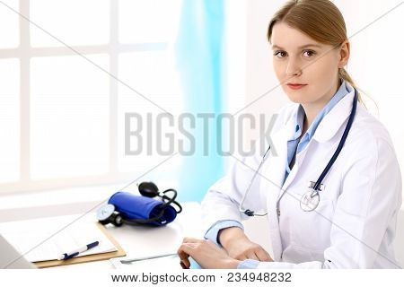 Female Doctor Filling Up Medical Form On Clipboard.  Physician Looking At Camera. Healthcare, Insura