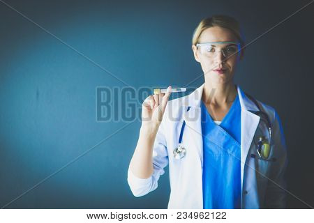 Female medical or research scientist or doctor using looking at a test tube of clear solution in a lab or laboratory.