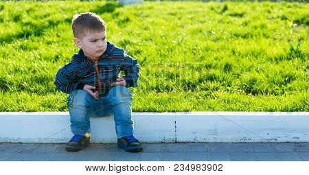 Serious Capricious Boy Is Sitting On The Road