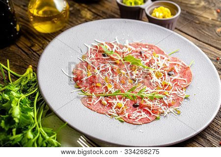 Rustic Wooden Background, Top And Side, On A Round Plate, Appetizer Stroganina From Marbled Beef Wit