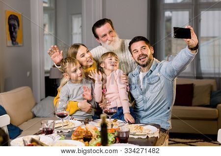 Portrait Of Happy Multi Generation Family Taking Selfie Photo Sitting At Dinner Table While Celebrat