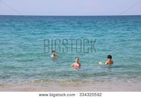 Two Boy And A Little Girl On The Water Of Ocean In Summer