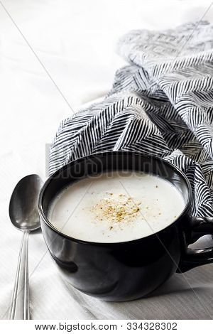 Cauliflower Soup (creme Du Barry) In Black Bowl On White Background With Black And White Cloth