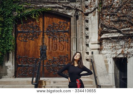 Stylish Brunette Standing Next To The Entance To A Building