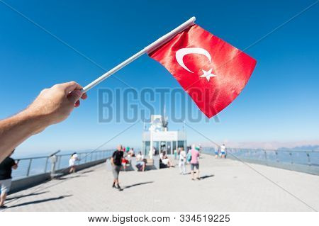 Bright Red Flag Of Turkey With A Star And Moon In The Hands Of A Man Tourist On The Background Of Th