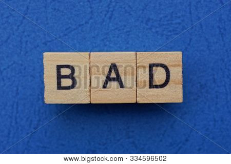 Word Bad Made From Brown Wooden Letters Lies On A Blue Table