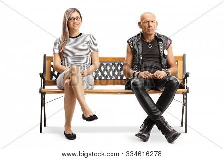 Full length portrait of a young blond woman and a grumpy punker sitting on a bench isolated on white background