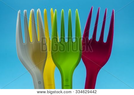 Yellow Pink Green And White Cutlery Plastic Forks Arranged On Blue Background. Color Trends And Recy