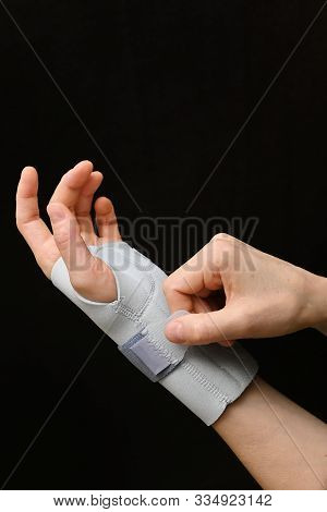 Contused Woman Hand In Stabilizer On Black Background