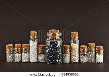 White, Beige, Yellow And Gray Beads In Glass Jars On Black Background. Beads In A Transparent Contai
