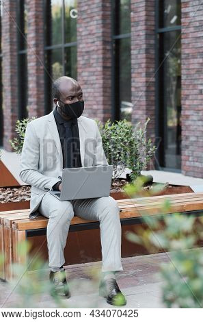 Vertical Shot Of Modern Unrecognizable African American Man Wearing Protective Mask On Face Sitting 