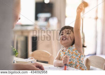 Cute Asia Baby Girl Drawing With Whte Paper On Wood Table At Home With Her Mother