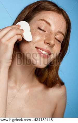 Close Up Of Redhead Girl Uses Gua Sha Massaging Scrapper On Face, Smiling From Pleasure, Enjoyes Mas